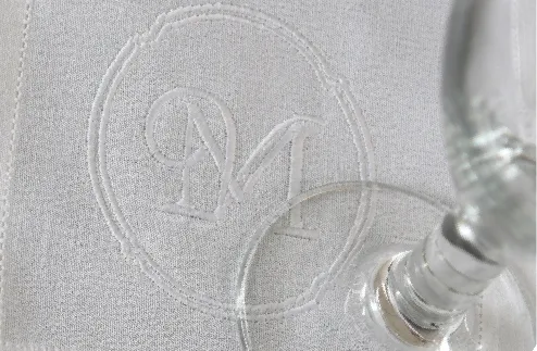 Servilleta de cóctel de lino blanco con monograma bordado bajo una copa de cristal